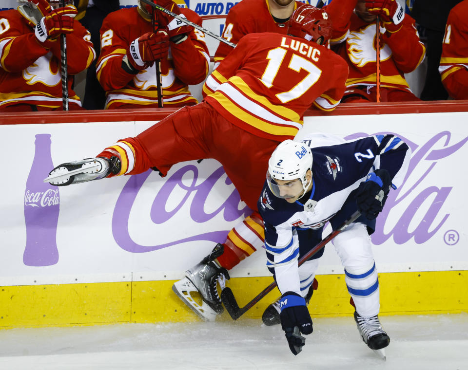 Winnipeg Jets defenseman Dylan DeMelo, right, checks Calgary Flames forward Milan Lucic during the second period of an NHL hockey game Saturday, Nov. 12, 2022, in Calgary, Alberta. (Jeff McIntosh/The Canadian Press via AP)