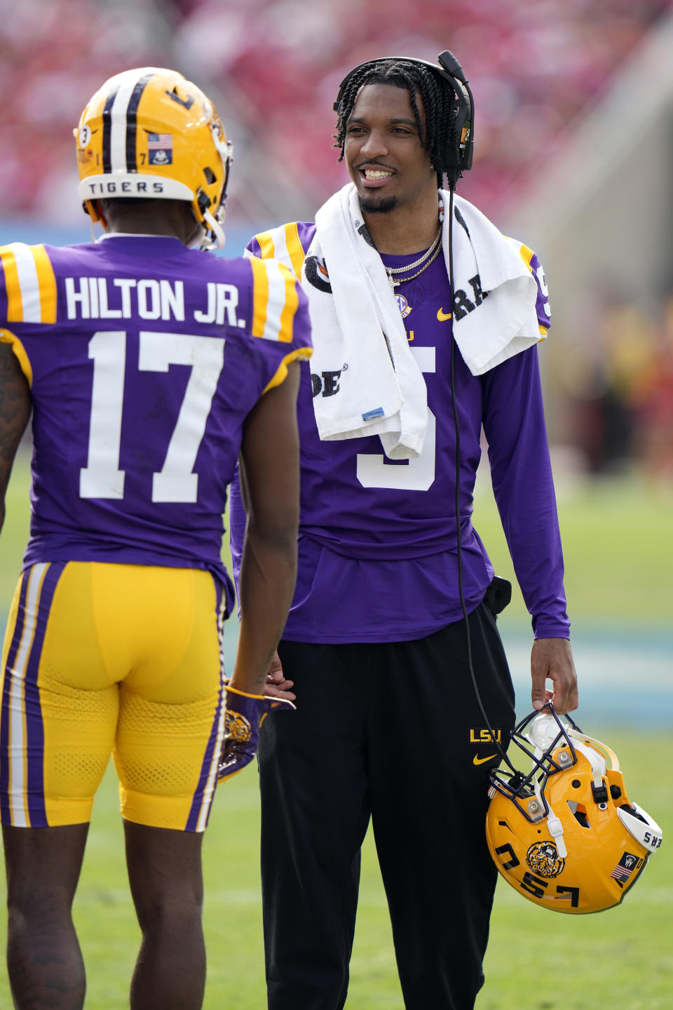 Heisman Trophy winning quarterback Jayden Daniels (5), of LSU, talks to wide receiver Chris Hilton Jr. (17) during the first half of the ReliaQuest Bowl NCAA college football game against Wisconsin Monday, Jan. 1, 2024, in Tampa, Fla. Daniels is not playing in the game. (AP Photo/Chris O'Meara)