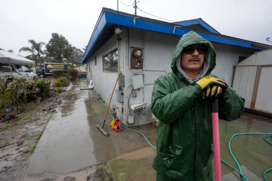 Ruben Gomez pauses as he digs away some of the mud and flood debris that engulfed his parents’ home in the previous rainstorm as more rain falls, Thursday, Feb. 1, 2024, in San Diego. Gomez has spent all of his time since the Jan. 22 storm shuttling between caring for his parents who were rescued by boat and later hospitalized that day, and trying to salvage what he can from the flooded home. Now, with more rain coming, Gomez worries the floodwaters may rise again in his parents’ neighborhood. (AP Photo/Gregory Bull)