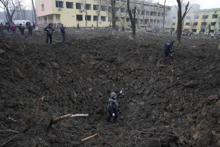 FILE - Ukrainian soldiers and emergency employees work outside a maternity hospital damaged by shelling in Mariupol, Ukraine, Wednesday, March 9, 2022. An Associated Press team of journalists was in Mariupol the day of the airstrike and raced to the scene. Their images prompted a massive Russian misinformation campaign that continues to this day. (AP Photo/Evgeniy Maloletka, File)