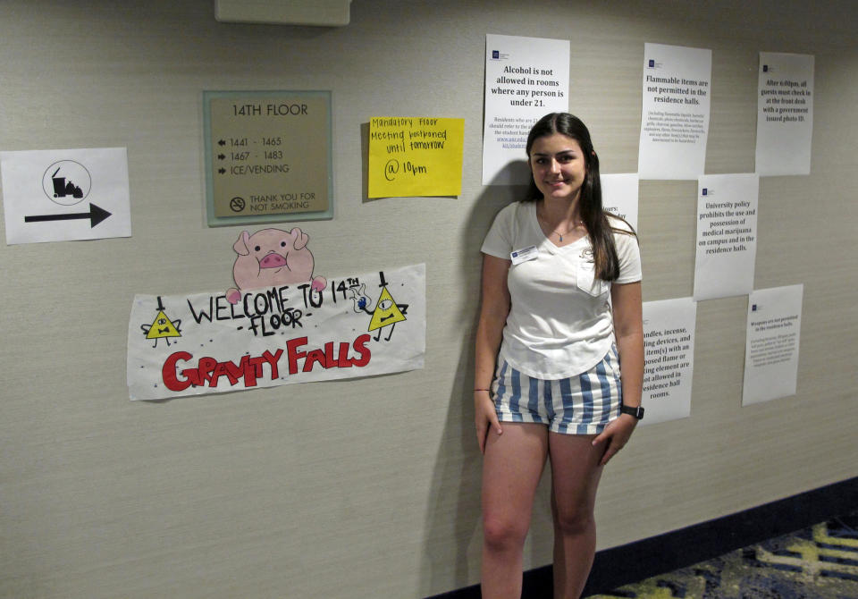 In this photo taken Monday, Aug. 19, 2019, Kailyn JBeily, a resident assistant at the University of Nevada, Reno, poses in the hallway outside her room in a Circus Circus casino hotel tower in downtown Reno, Nev., that has been converted into a dormitory a half-mile from the main campus. Now called Wolf Pack Tower, it will house about 1,300 UNR students for the coming school year after a July gas explosion shut down the two largest dorms. (AP Photo/Scott Sonner)