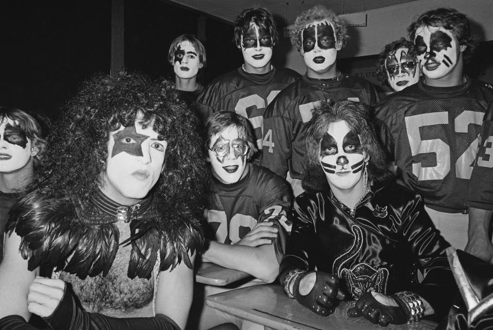 Stanley and drummer Peter Criss pose with the Cadillac High School football team during the 'Day in the Life of a Town' in Cadillac, Michigan on October 9, 1975. (Photo by Fin Costello/Redferns) 