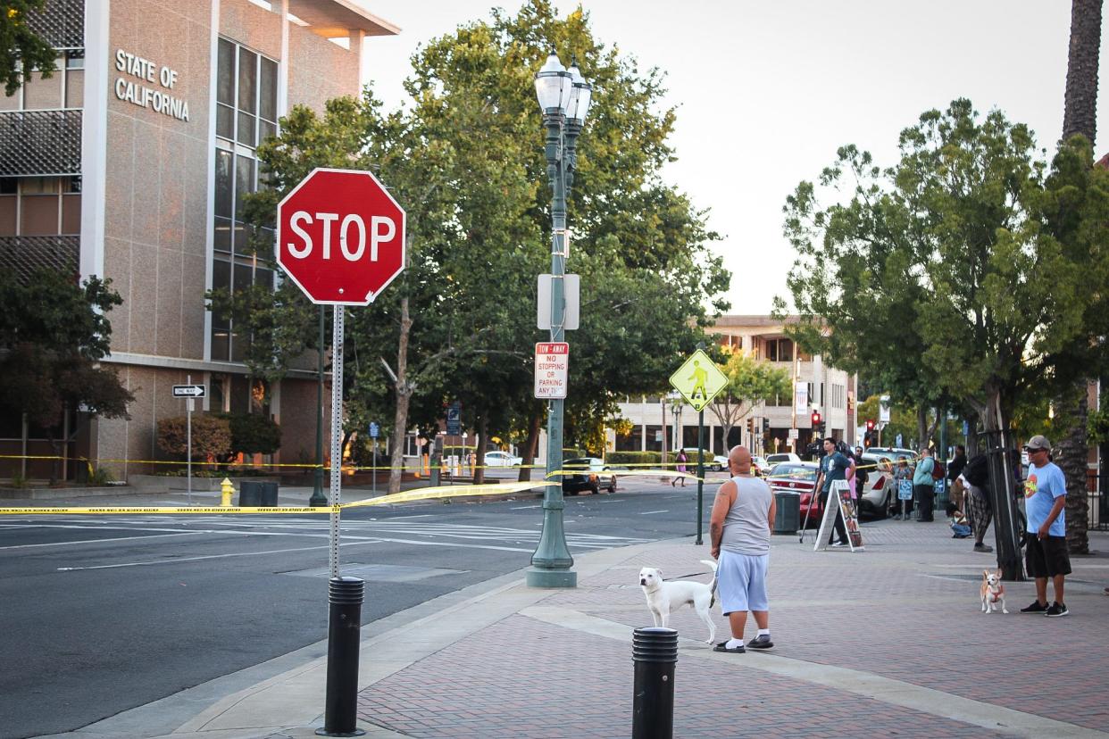 People watch as investigators gather evidence after a 15-year-old and a 16-year-old were shot near the Regal theater in downtown Stockton on Monday, Sept. 25, 2023.