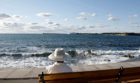 A woman sits at the embankment in the Black Sea city of Sevastopol September 14, 2008. REUTERS/Denis Sinyakov/File Photo