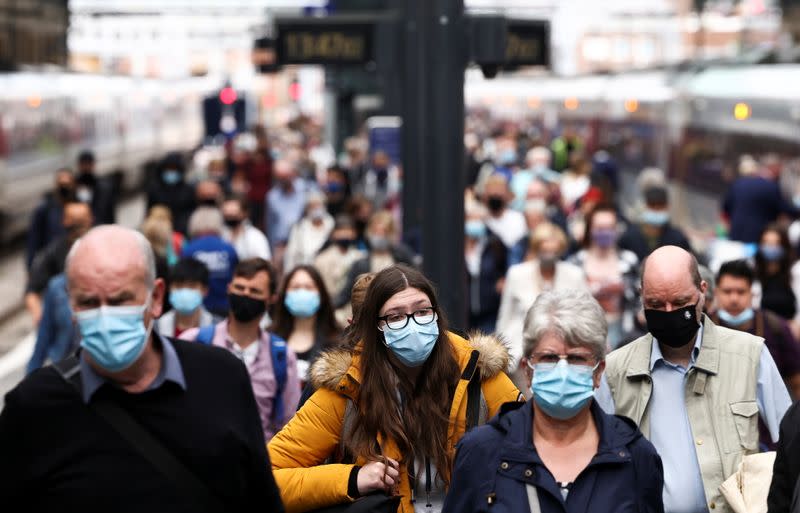 People wearing protective face masks walk along a platform at King's Cross Station, amid the coronavirus disease (COVID-19) outbreak in London