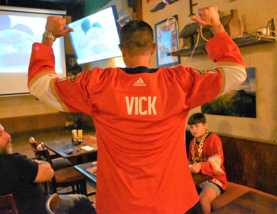 Florida Panthers fan Bryan Vick points to his custom jersey as he and his two sons join friend Aramas Kaloustian at O'Shea's to watch the Panthers play Edmonton.