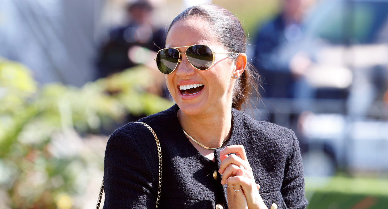 meghan markle in black jacket, black sunglasses and purse laughing at invictus games 2022