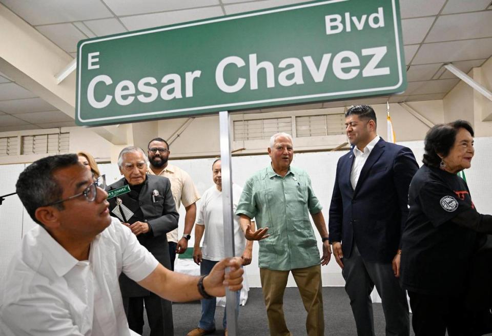 El concejal de Fresno Miguel Arias, a la izquierda, planta el letrero simbólico de la calle en frente del escenario después de que se dio a conocer ante cientos de personas durante la celebración del cambio de nombre de la calle en honor a César E. Chávez, realizada en el recinto ferial de Fresno, el sábado 10 de junio de 2023, en Fresno.