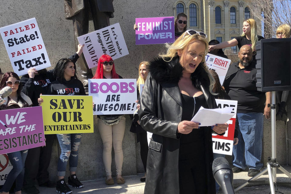 Adult film star Stormy Daniels reads a statement, protesting the Illinois surcharge on live adult entertainment centers, beneath the statue of Abraham Lincoln at the state Capitol, Friday, March 22, 2019 in Springfield, Ill. The actress famous for her alleged affair with Donald Trump before he became president read a two-minute statement before she was whisked off to a local strip club to sign copies of her book. Daniels, whose real name is Stephanie Clifford, says the tax unfairly ties nude dancing to violence against women and that it "takes money out of the g-strings of hardworking young dancers." (AP Photo/John O'Connor)