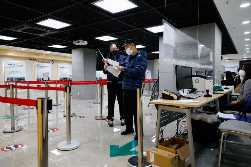 Men check a mandatory document to get an influenza vaccine at a branch of the Korea Association of Health Promotion in Seoul