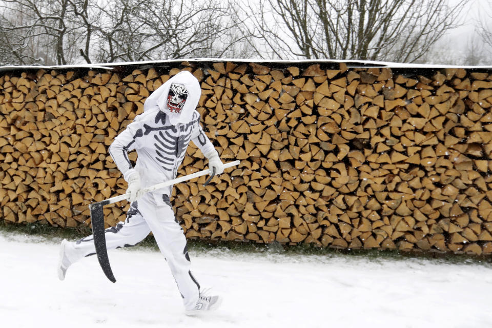 A reveler depicting a grim reaper runs during a traditional St Nicholas procession in the village of Valasska Polanka, Czech Republic, Saturday, Dec. 7, 2019. This pre-Christmas tradition has survived for centuries in a few villages in the eastern part of the country. The whole group parades through village for the weekend, going from door to door. St.Nicholas presents the kids with sweets. The devils wearing home made masks of sheep skin and the white creatures representing death with scythes frighten them. (AP Photo/Petr David Josek)