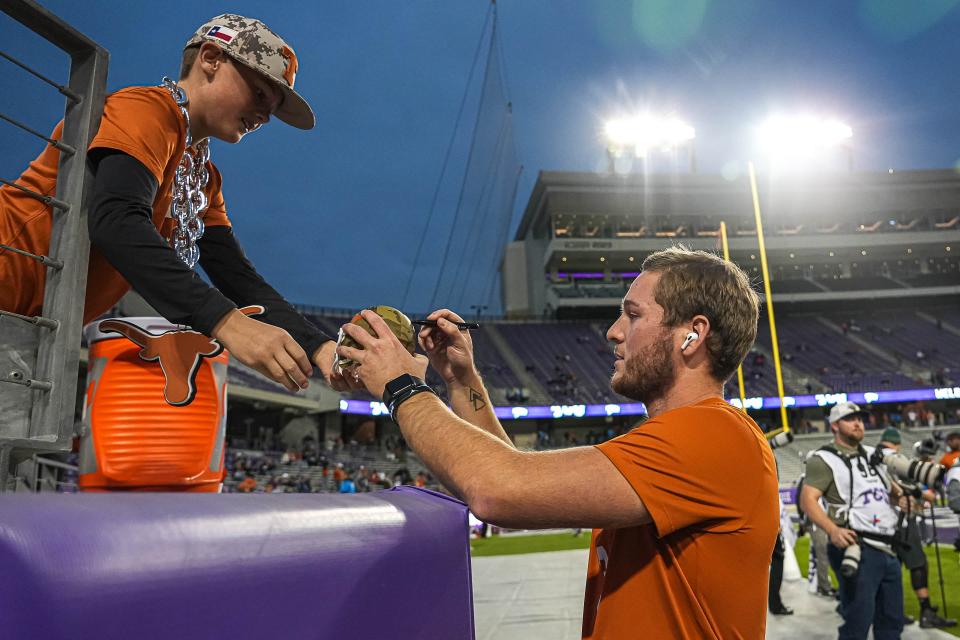 Texas quarterback Quinn Ewers signs a ball for UT fan Riley Dozier before last Saturday night's 29-26 win over TCU at Amon G. Carter Stadium in Fort Worth. The Longhorns have two regular-season games left against Iowa State and Texas Tech.