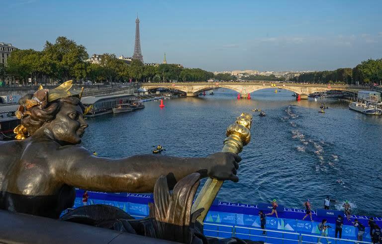 Foto del jueves 17 de agosto del 2023, atletas saltan y nadan en el río Sena cerca del puente Alexander III en la primera etapa del evento de prueba del triatlón para los Juegos Olímpicos 2024. (AP Foto/Michel Euler)