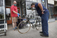 In this Tuesday, June 9, 2020 photo, Harvey Curtis, left, discusses repair plans with customer Jack Matheson outside Sidecountry Sports, a bike shop in Rockland, Maine. Matheson is looking forward to getting his 40-year-old Raleigh back on the road. (AP Photo/Robert F. Bukaty)