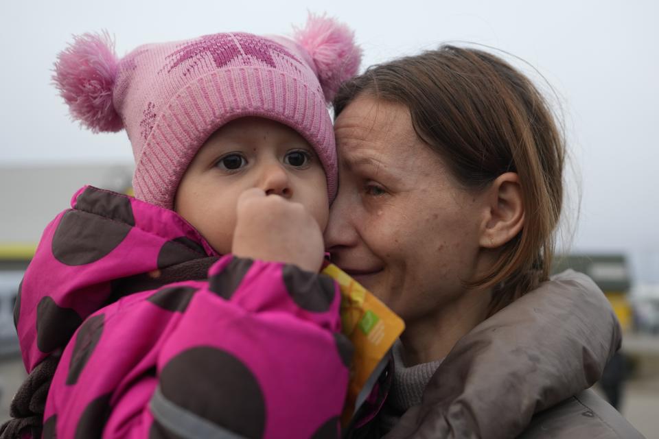 A women with a child who fled from the war in Ukraine reacts as they reuniting with their family after crossing the border Tuesday in Medyka, Poland.