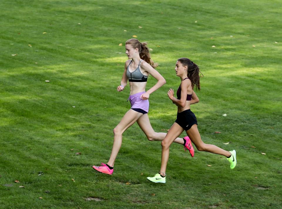 Central Kitsap sophomore Clare Herring, left, and freshman Audra Palmer run the team's course through the Anderson Hill Athletic Fields complex during practice on Wednesday, Oct. 12, 2022.