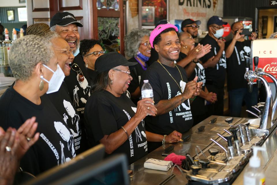 Jabee Williams, center, stands with Marilyn Luper Hildreth and the rest of the original Oklahoma City sit-in participants behind the counter of Kaiser’s Grateful Bean Café during the 2022 sit-in reenactment.
