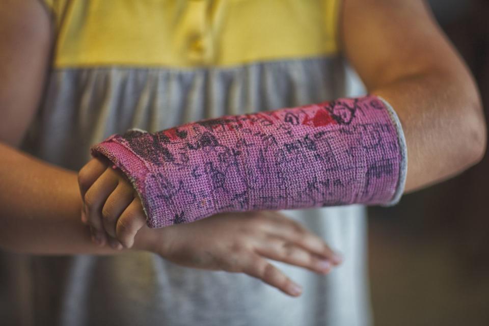 midsection of girl showing her signed arm cast