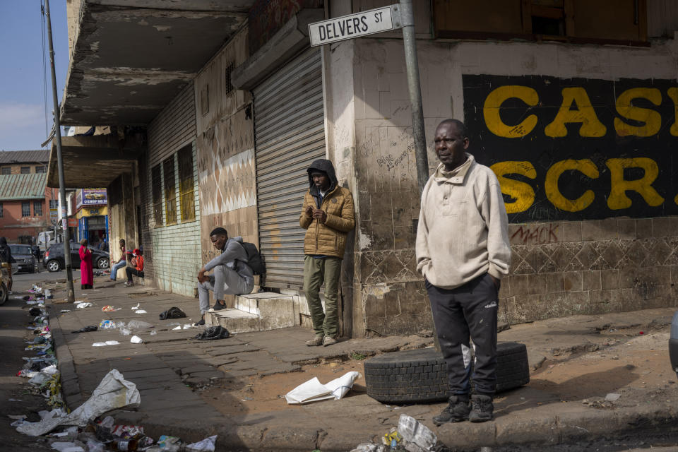 FILE - Neighbourhood residents stand near the scene of one of South Africa's deadliest inner-city fires in Johannesburg, South Africa, Friday, Sept. 1, 2023. Syndicates take over rundown buildings and collect rent from locals and migrants desperate for accommodation. They are surrounded by uncollected rubbish and are often a hub for criminals including robbers and drug dealers. (AP Photo/Jerome Delay, file)