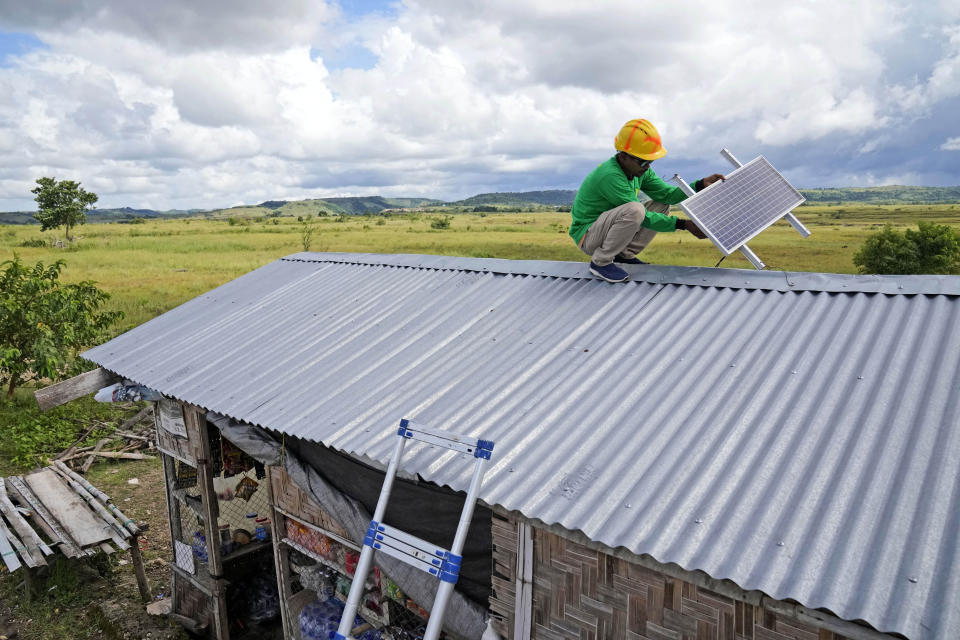 Antonius Makambombu, a worker of Sumba Sustainable Solutions, performs maintenance work on a solar panel on the roof of a customer's shop in Laindeha village on Sumba Island, Indonesia, March 22, 2023. Up to 2.3 billion people around the world are still using polluting fuels to cook and 675 million don't have electricity, according to a report released Tuesday by five international organizations. (AP Photo/Dita Alangkara)