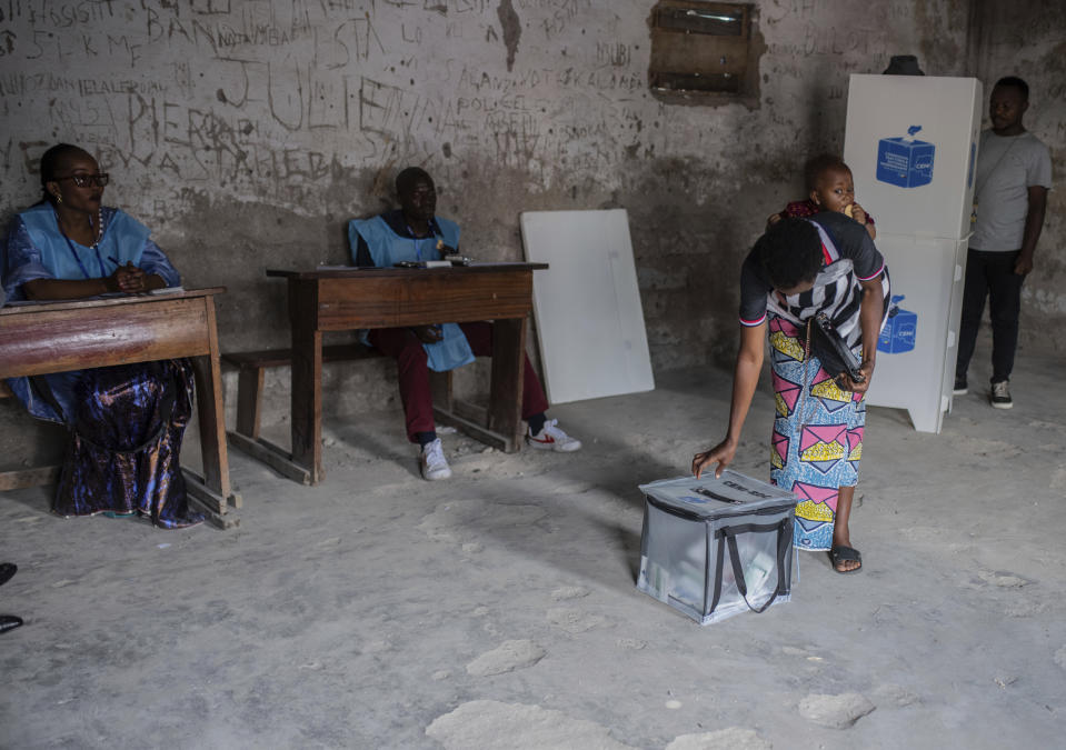 A woman with a baby strapped on her back, casts her vote at a polling station in Goma, eastern Democratic Republic of the Congo, Wednesday, Dec. 20, 2023. Congo headed to the polls Wednesday to vote for president as authorities scrambled to finalise preparations in an election facing steep logistical and security challenges. (AP Photo/Moses Sawasawa)