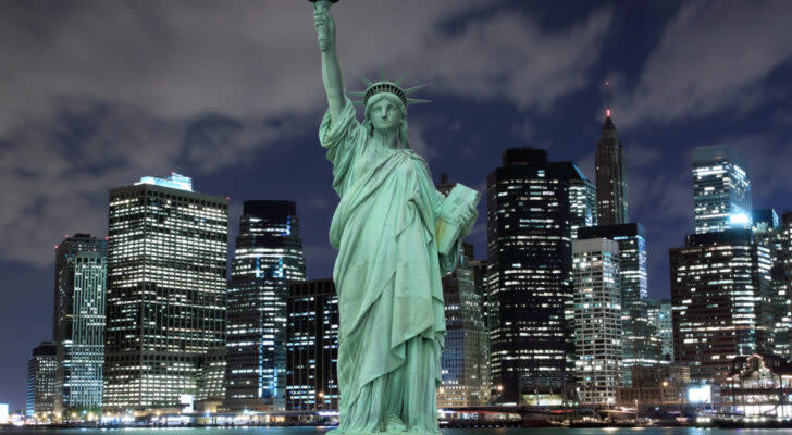 a backlit photograph of the statue of liberty against the skyscrapers of NYC