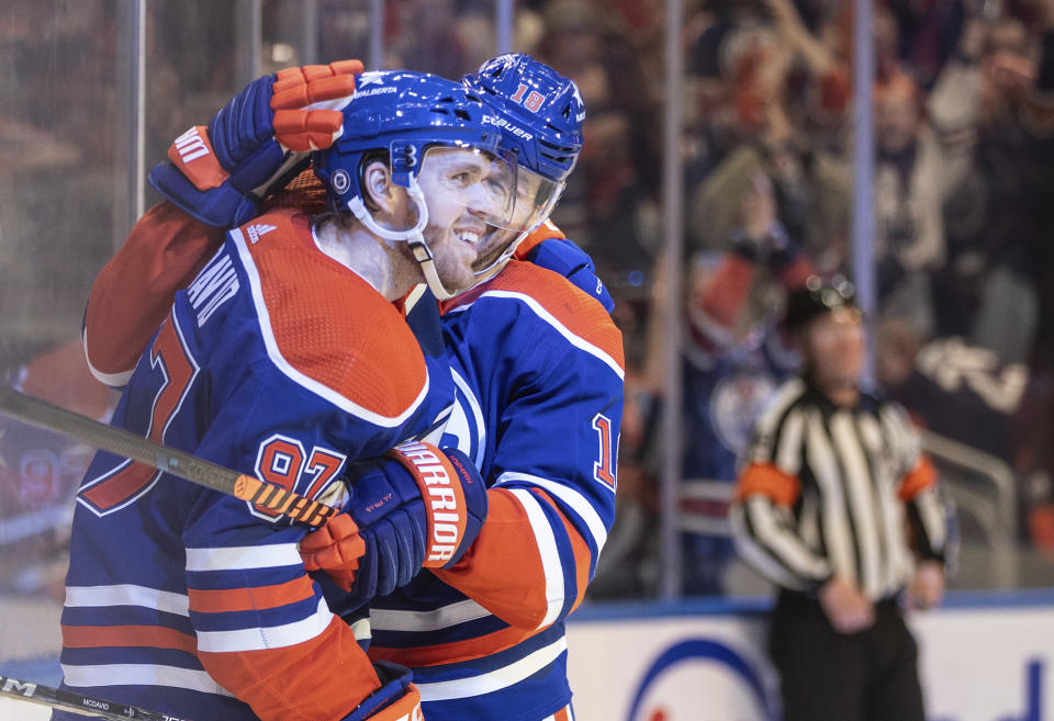 Edmonton Oilers' Connor McDavid (97) celebrates his 100th assist this season with Zach Hyman (18) against the San Jose Sharks during the second period of an NHL hockey game in Edmonton, Alberta, on Monday, April 15, 2024. (Jason Franson/The Canadian Press via AP)