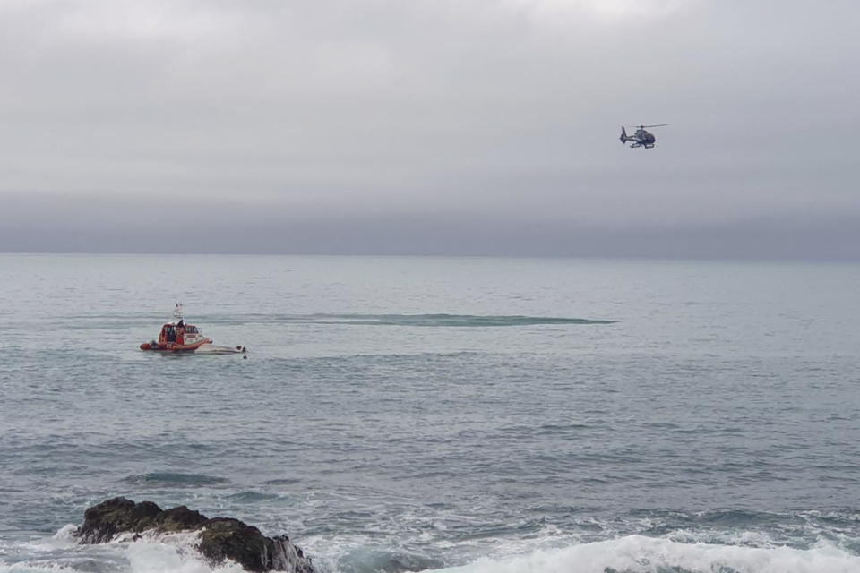 A helicopter and a rescue boat search for survivors off the coast of Kaikoura, New Zealand, Saturday, Sept. 10, 2022. A boat in New Zealand collided with a whale and capsized. (AP Photo)