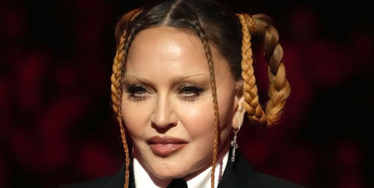 madonna pictured at the grammy awards, wearing a black tie suit jacket with a white colour, her hair partly in braids
