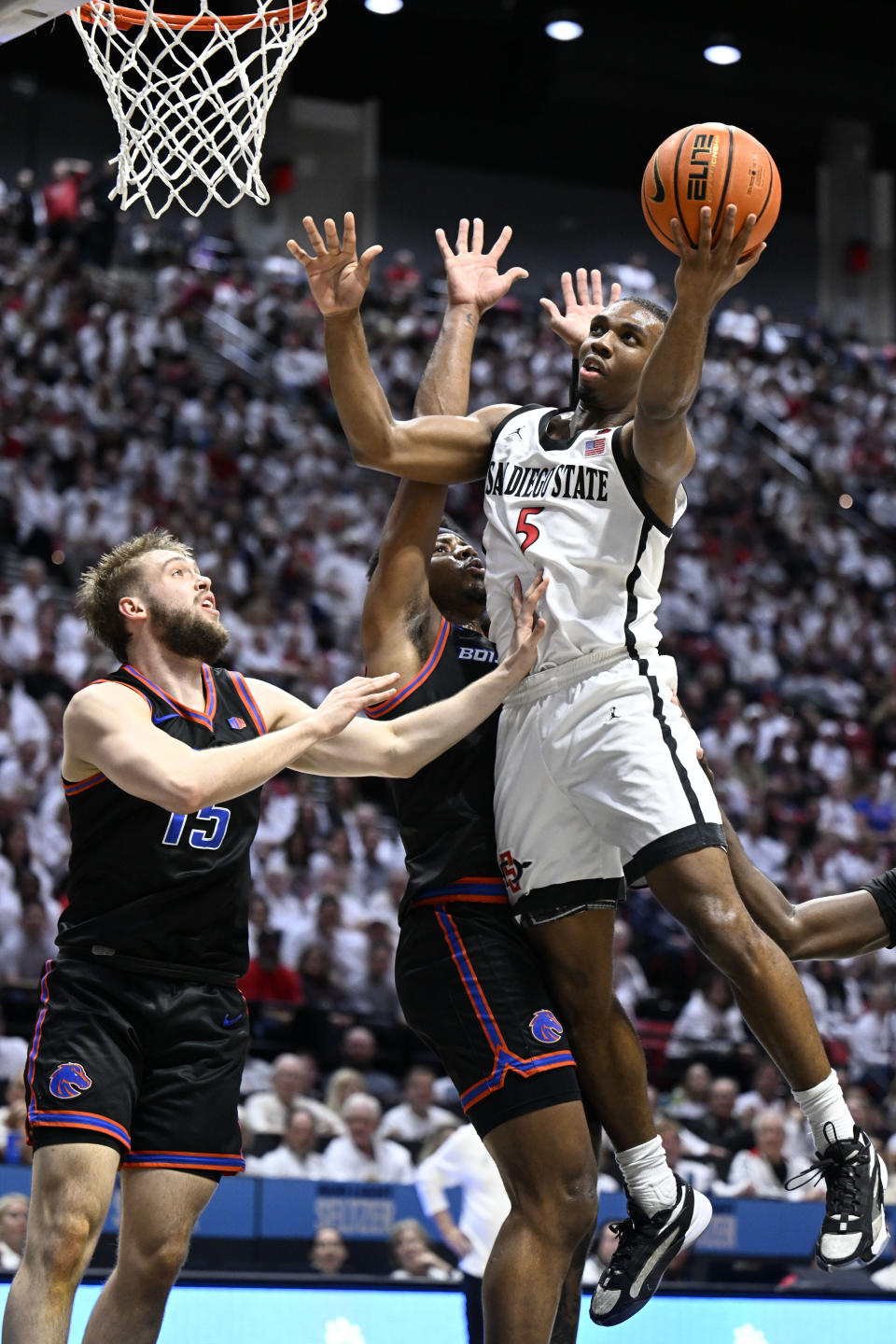 San Diego State guard Lamont Butler (5) shoots against Boise State guard Jace Whiting (15) and guard Chibuzo Agbo (11) during the second half of an NCAA college basketball game Friday, March 8, 2024, in San Diego. (AP Photo/Denis Poroy)