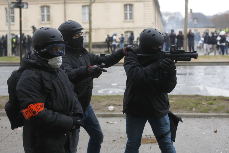 A police officer aims after a yellow vest march Saturday, Jan. 19, 2019 in Paris. Thousands of yellow vest protesters rallied Saturday in several French cities for a 10th consecutive weekend, despite a national debate launched this week by President Emmanuel Macron aimed at assuaging their anger. (AP Photo/Thibault Camus)