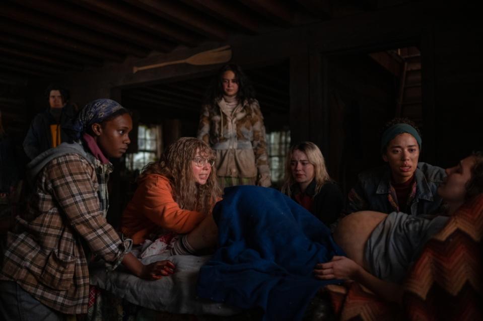 (L-R): Kevin Alves as Teen Travis, Nia Sondaya as Teen Akilah, Samantha Hanratty as Teen Misty, Courtney Eaton as Teen Lottie, Sophie Thatcher as Teen Natalie, Jasmin Savoy Brown as Teen Taissa and Sophie Nélisse as Teen Shauna in YELLOWJACKETS, "Qui". Photo Credit: Kailey Schwerman/SHOWTIME.