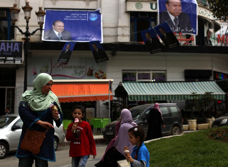 A woman and her daughter walk past posters of Abdelaziz Bouteflika, bidding to remain presidents in the upcoming elections, in the center of Algiers on April 15, 2014