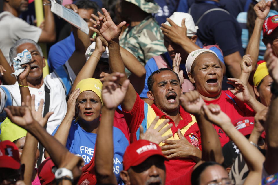 Militia members and supporters of Venezuela's President Nicolas Maduro sing an anthem to late former President Hugo Chavez, outside Miraflores presidential palace in Caracas, Venezuela, Monday, May 20, 2109. Maduro is celebrating the anniversary of his disputed re-election amid a growing humanitarian crisis and political upheaval. (AP Photo/Ariana Cubillos)