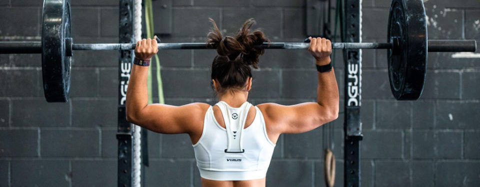 Back of woman lifting weights wearing smar watch best buy