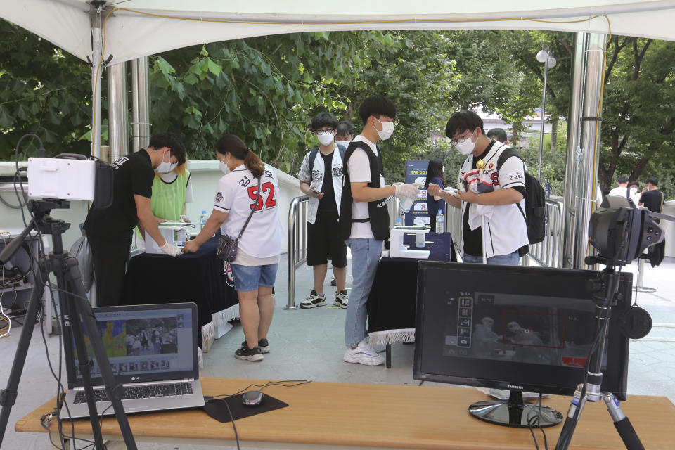 Fans wearing face masks to help protect against the spread of the new coronavirus arrive to watch the KBO league game between Doosan Bears and LG Twins in Seoul, South Korea, Sunday, July 27, 2020. South Korean Baseball Organization (KBO) on Sunday started admitting fans to the games but only at 10% capacity for each venue.(AP Photo/Ahn Young-joon)