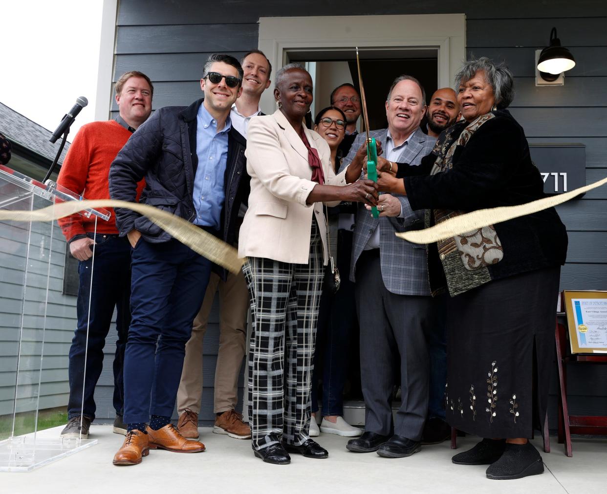 (Center left to right) With others watching, Martha Coates, president of the East Village Association, Detroit Mayor Mike Duggan and Delores Orr, East Village Association vice president cut the ribbon in front of a Greatwater Opportunity Capital home on Fischer Street in Detroit on Thursday, May 9, 2024.