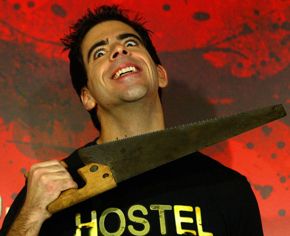 Eli Roth holds a saw to his neck posing for photographers while promoting Hostel in 2006. (Getty)
