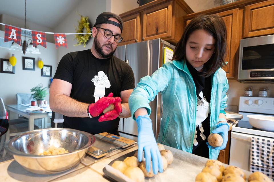 Christapher Garcia and his daughter Kennedi, 8, prepare a large batch of Kennadi's Kookies at their home on Tuesday, Dec. 20, 2022.