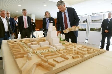 CEO Severin Schwan (2nd R) of Swiss drugmaker Roche talks to journalists as he stands beside a scale model of the Roche headquarters during a news conference in Basel October 22, 2014. REUTERS/Arnd Wiegmann