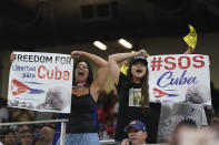 Demonstrators hold up signs and chant during the sixth inning of a World Baseball Classic game between Cuba and the U.S., Sunday, March 19, 2023, in Miami. (AP Photo/Wilfredo Lee)