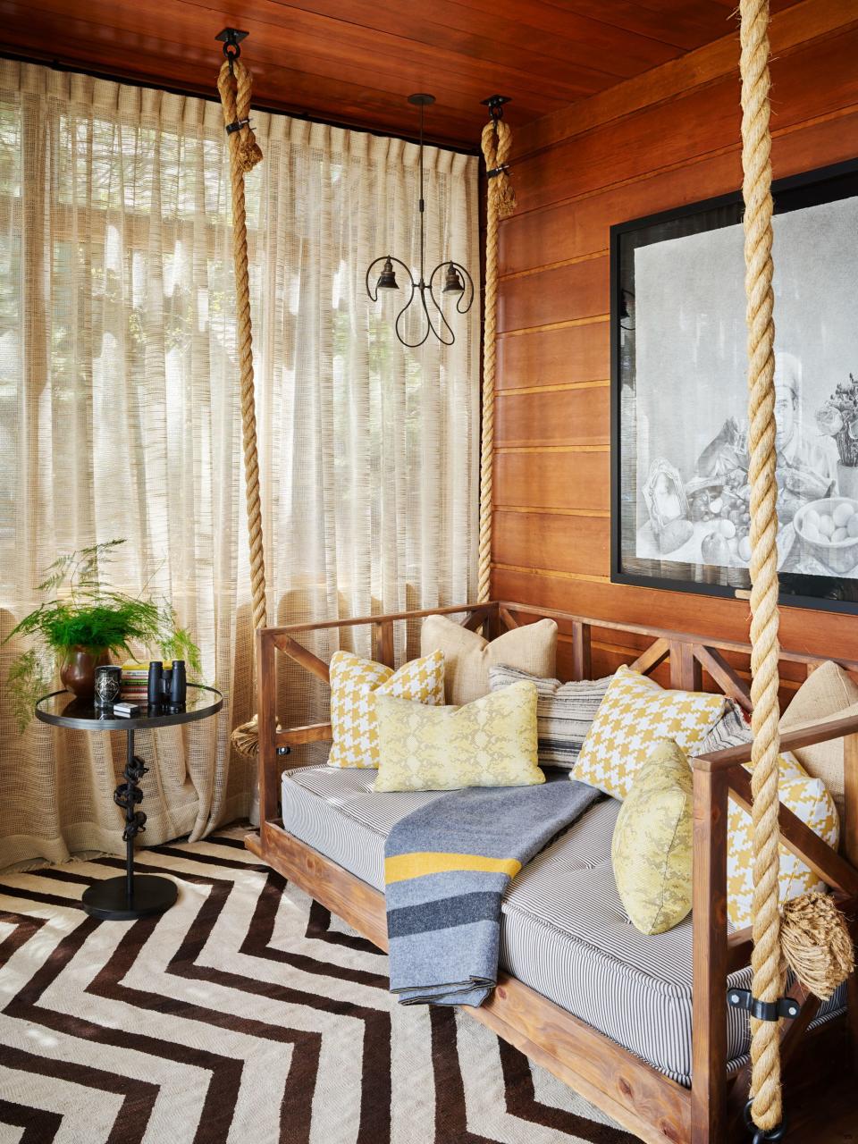The sunroom features a suspended daybed by Robert Buckley. Cushion wears a Perennials stripe; curtains of an Opuzen sheer; Ethan Murrow drawing; Krimsa rug.