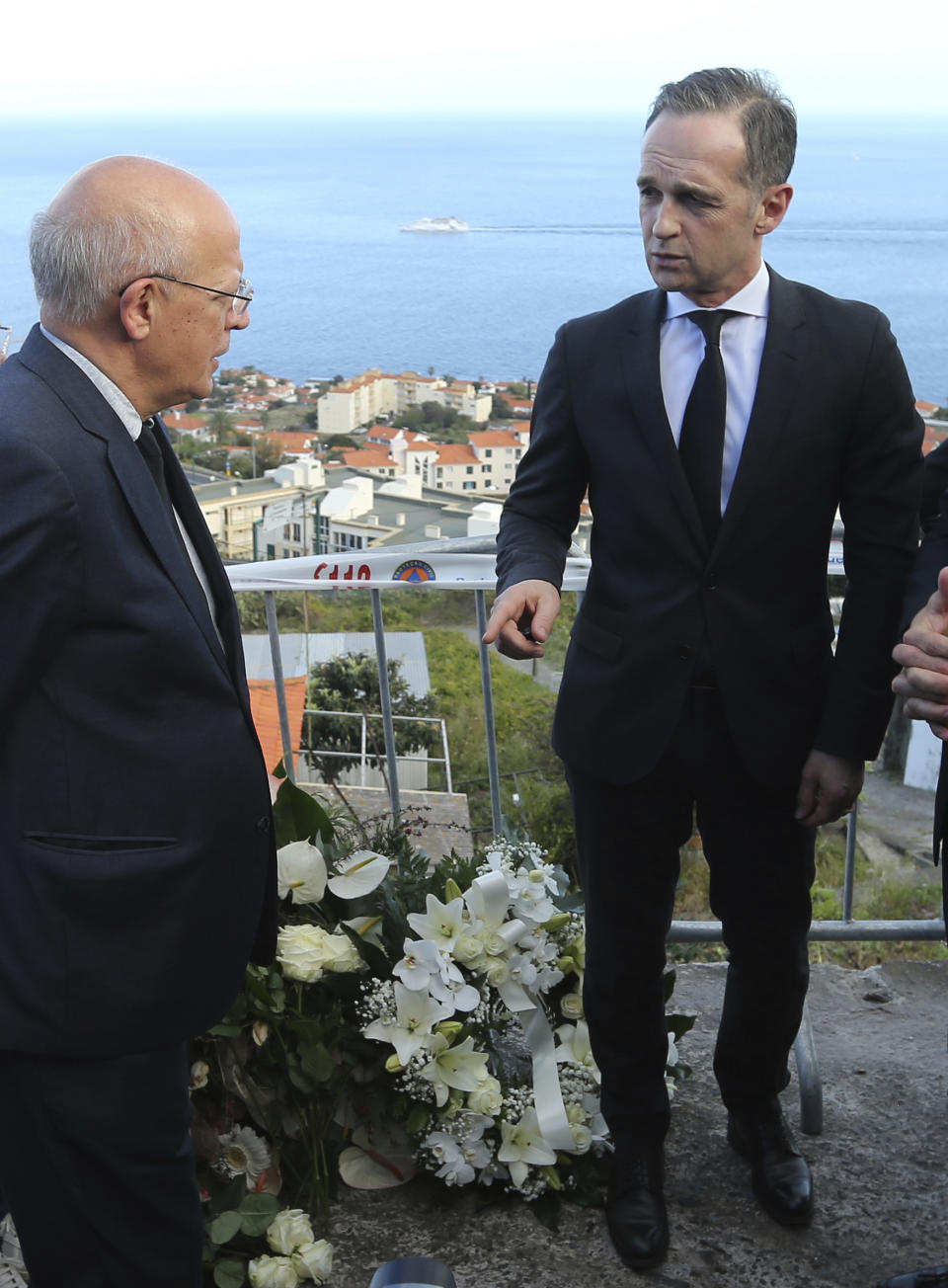 German Foreign Minister Heiko Maas, right, and Portuguese Foreign Minister Augusto Santos Silva visit near the scene where a bus crashed in Canico, on Portugal's Madeira Island, Thursday April 18, 2019. All the 29 people killed in a bus crash on Portugal's Madeira Island were German, Portugal's foreign ministry confirmed Thursday. The bus carrying 55 people, all but two of them German tourists, rolled down a steep hill after veering off the road on a bend east of Madeira's capital, Funchal, on Wednesday evening when it was still light and in fine weather. The crash injured 28 others. (AP Photo/Armando Franca)