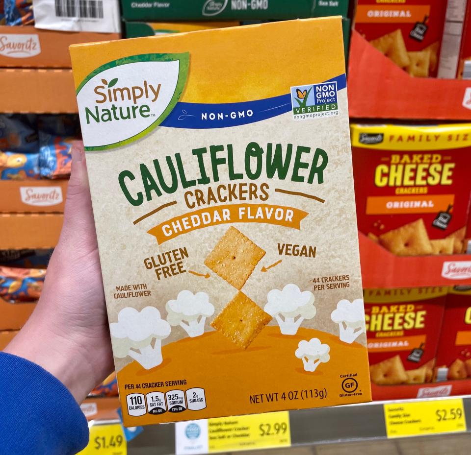 Hand holding Aldi cauliflower cheese crackers in orange box