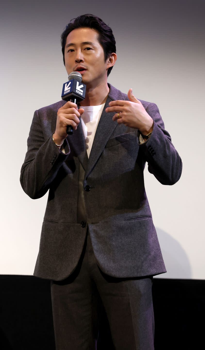 steven yeun talking and holding a microphone