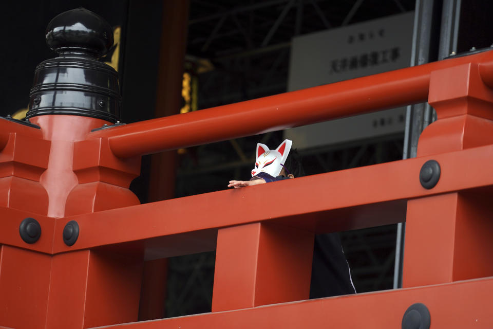 A child wearing traditional mask depicting fox pauses at a shrine Tuesday, Nov. 24, 2020, in Tokyo. The Japanese capital confirmed more than 180 new coronavirus cases on Tuesday. (AP Photo/Eugene Hoshiko)