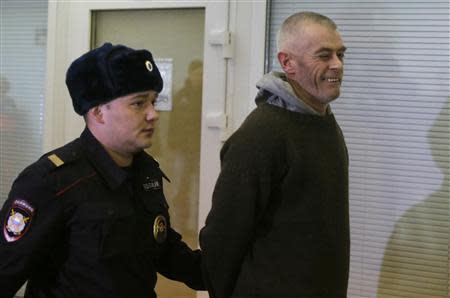 Greenpeace activist David John Haussmann (R) of New Zealand, one of the 30 people who were arrested over a Greenpeace protest at the Prirazlomnaya oil rig, winks while being escorted inside a court building in St. Petersburg, November 19, 2013. REUTERS/Alexander Demianchuk