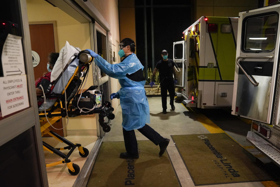 FILE - In this Jan. 8, 2021, file photo, emergency medical technician Thomas Hoang, 29, of Emergency Ambulance Service, pushes a gurney into an emergency room to drop off a COVID-19 patient in Placentia, Calif. Coronavirus hospitalizations are falling across the United States, but deaths have remained stubbornly high. (AP Photo/Jae C. Hong, File)