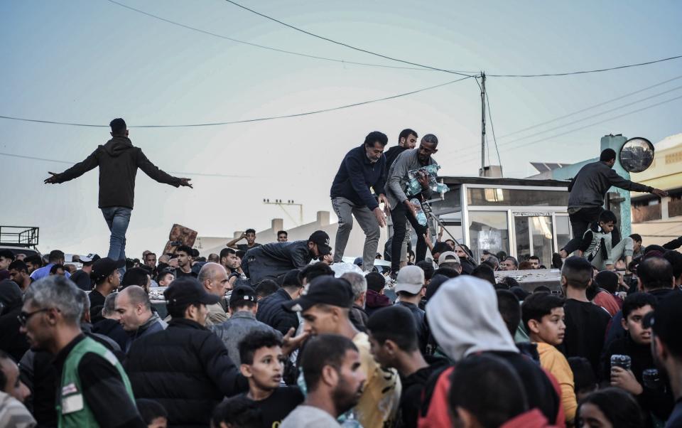 Palestinians flock around a truck carrying bottles of drinking water sent by Unicef amid water and food shortages due to Israeli attacks in Khan Yunis