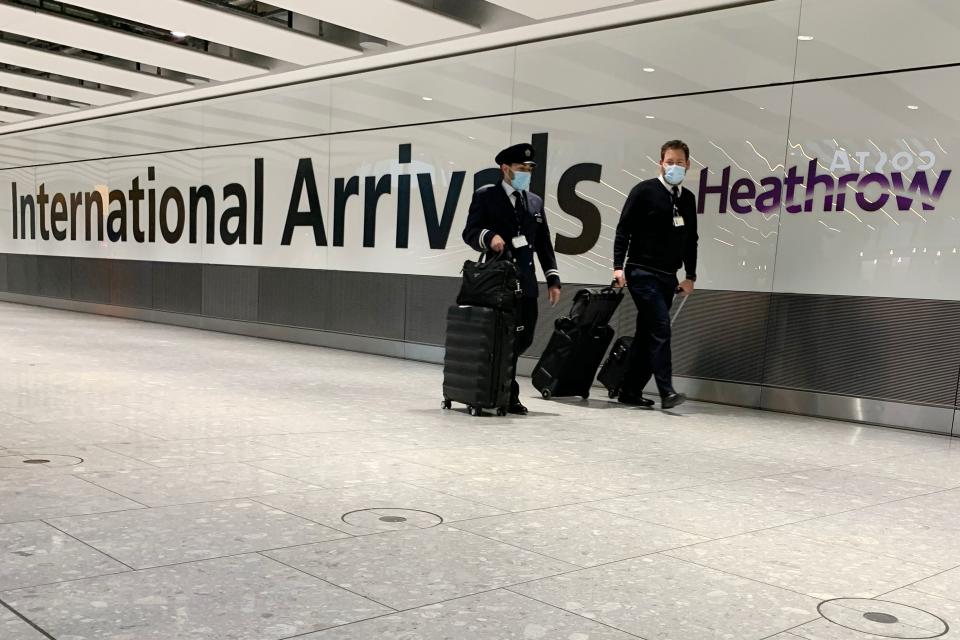 Flight crew wearing face masks because of the Covid-19 pandemic arrive at Terminal 5 at London Heathrow Airport in west London, on January 18, 2021. - All arrivals to the UK will have to quarantine and show negative tests for Covid-19 from today at 0400 GMT, after the government scrapped "travel corridors" from countries with lower caseloads following the emergence of new strains. (Photo by BEN STANSALL / AFP) (Photo by BEN STANSALL/AFP via Getty Images)